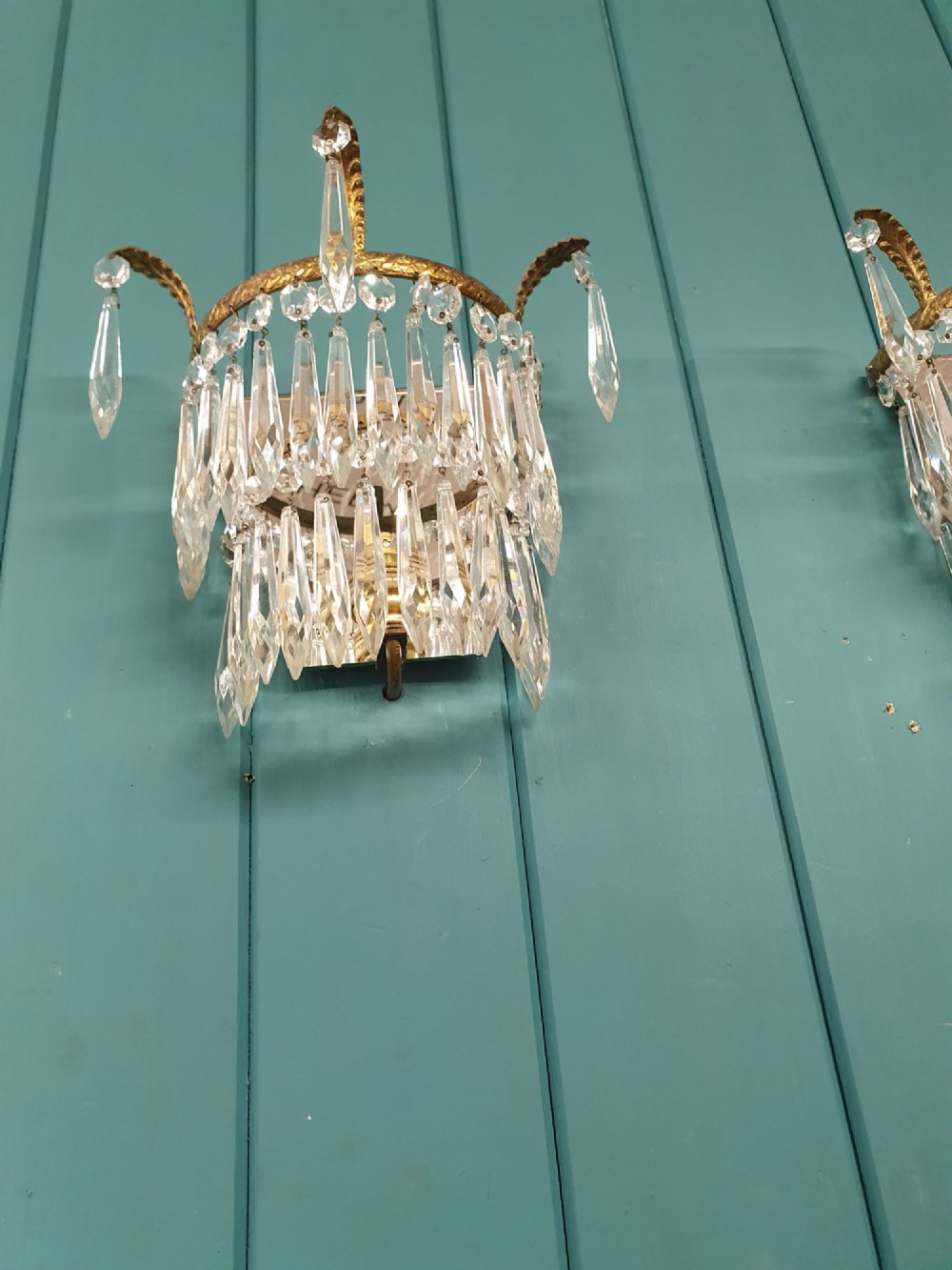 A pair of antique gilt brass wall lights adorned with cascading tiers of crystal spikes and glass drops. View IV