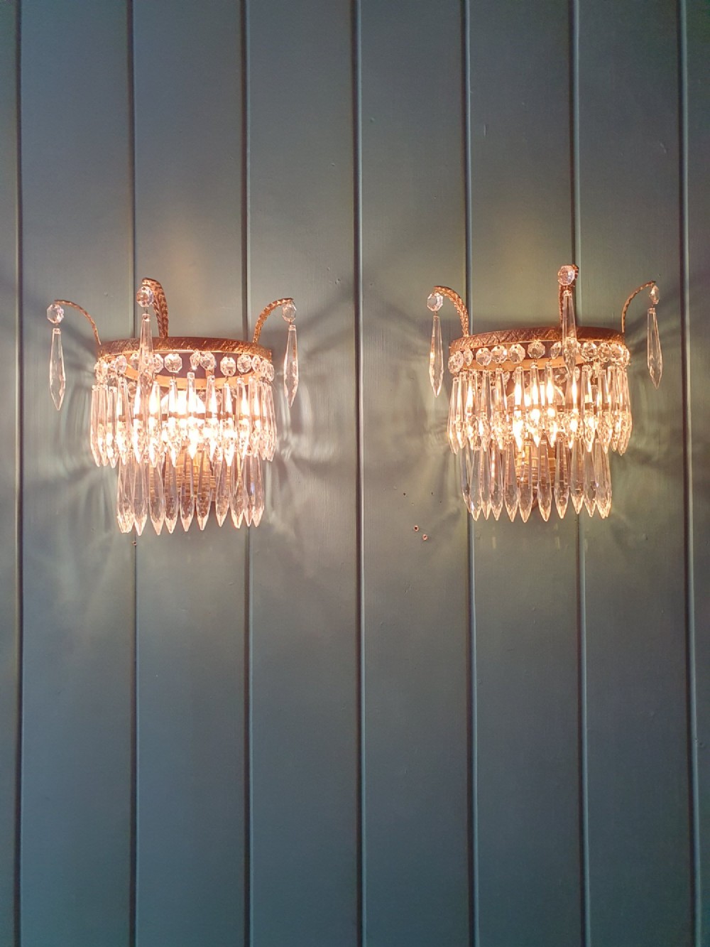 A pair of antique gilt brass wall lights adorned with cascading tiers of crystal spikes and glass drops. View V