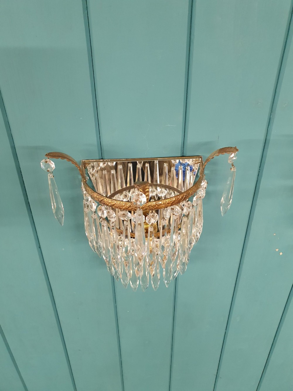 A pair of antique gilt brass wall lights adorned with cascading tiers of crystal spikes and glass drops. View VI