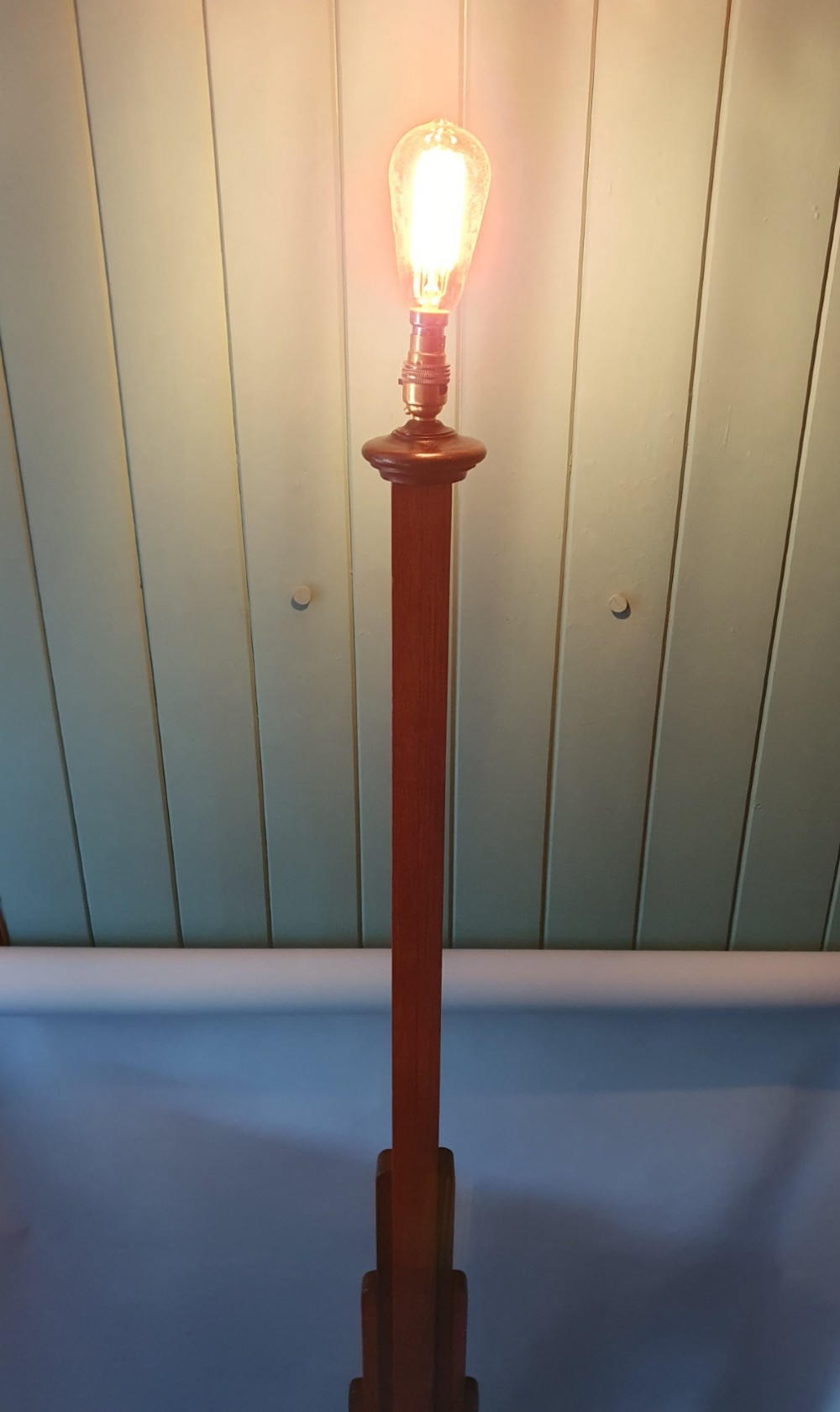 An Art Deco wooden standard lamp featuring a stepped skyscraper column design set upon a circular turned base with a brass light fitting. View II