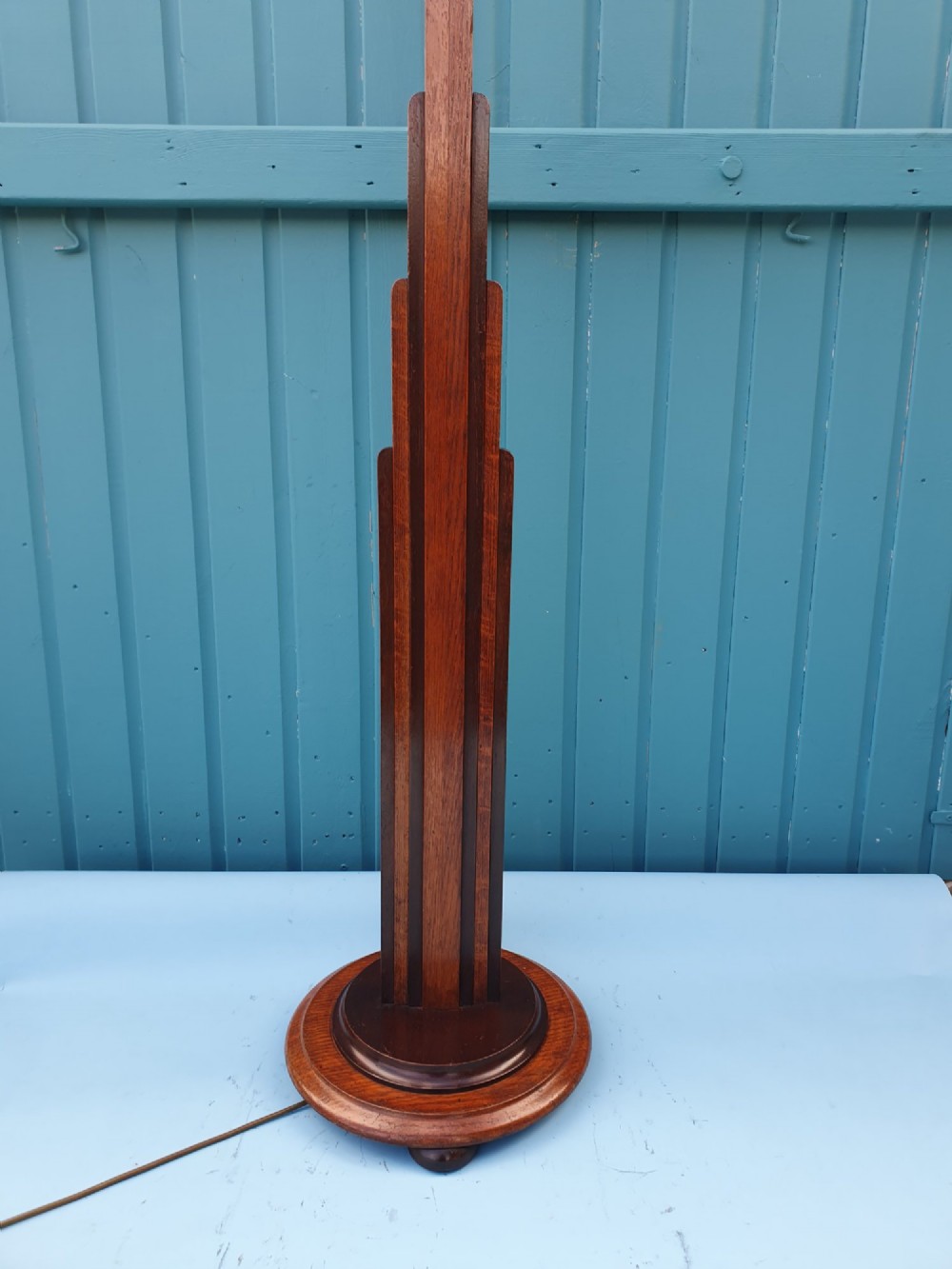 An Art Deco wooden standard lamp featuring a stepped skyscraper column design set upon a circular turned base with a brass light fitting. View V