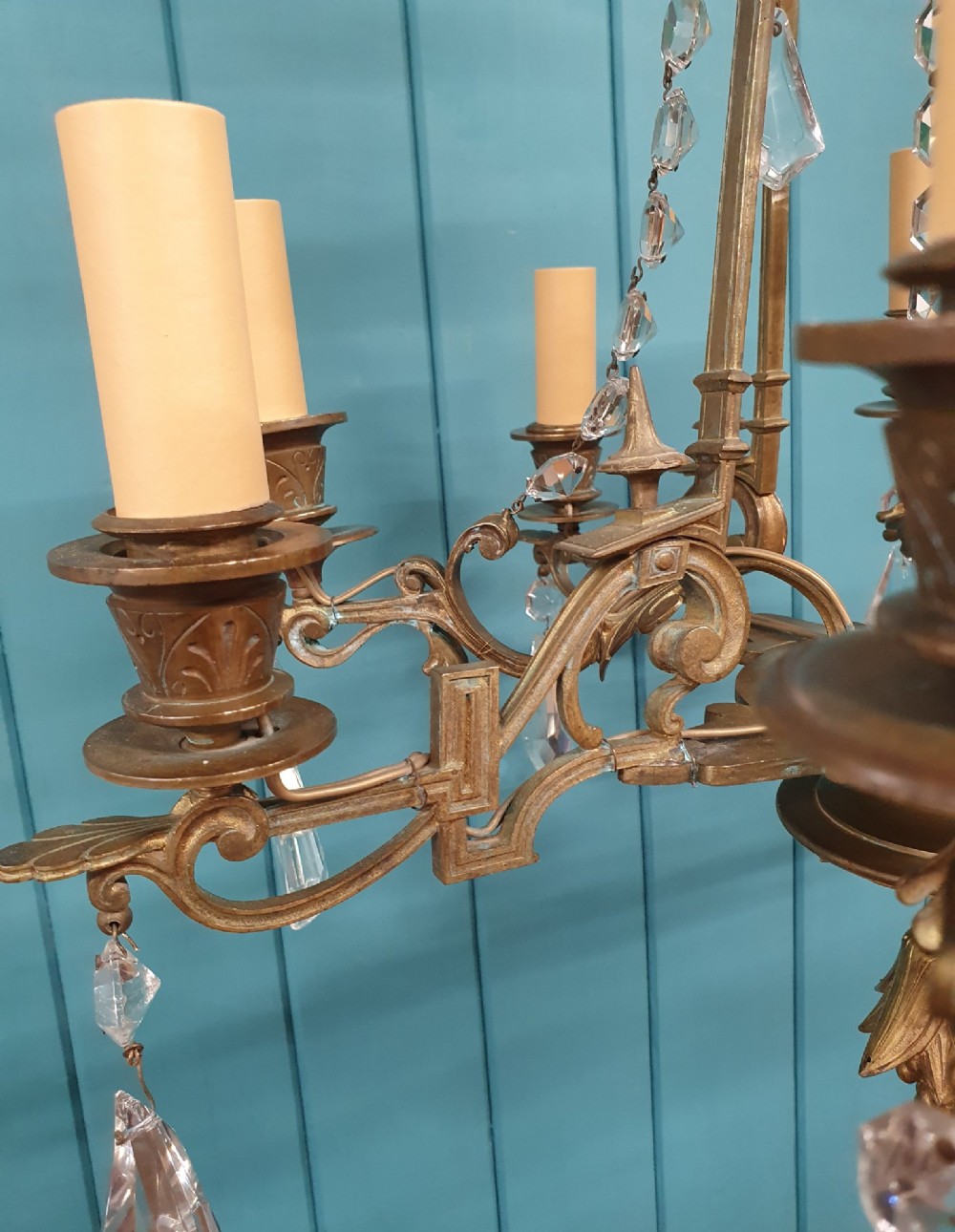 An antique eight-arm brass chandelier decorated with cut crystal drops, faceted beads, and cast lion mask details. View VII