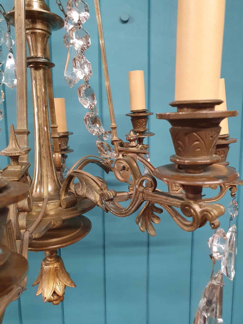 An antique eight-arm brass chandelier decorated with cut crystal drops, faceted beads, and cast lion mask details. View VIII