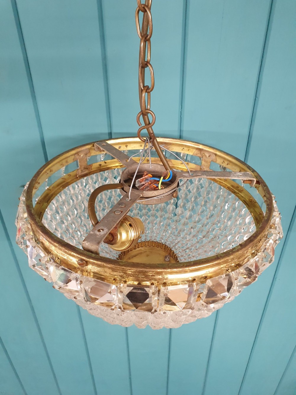 An early twentieth-century ceiling chandelier featuring a brass rim set with rectangular cut-glass prisms and a tapered bowl formed of clear glass beads ending in a faceted finial. View III