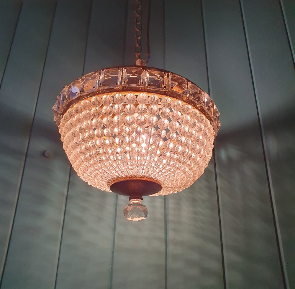 An early twentieth-century ceiling chandelier featuring a brass rim set with rectangular cut-glass prisms and a tapered bowl formed of clear glass beads ending in a faceted finial. View VII