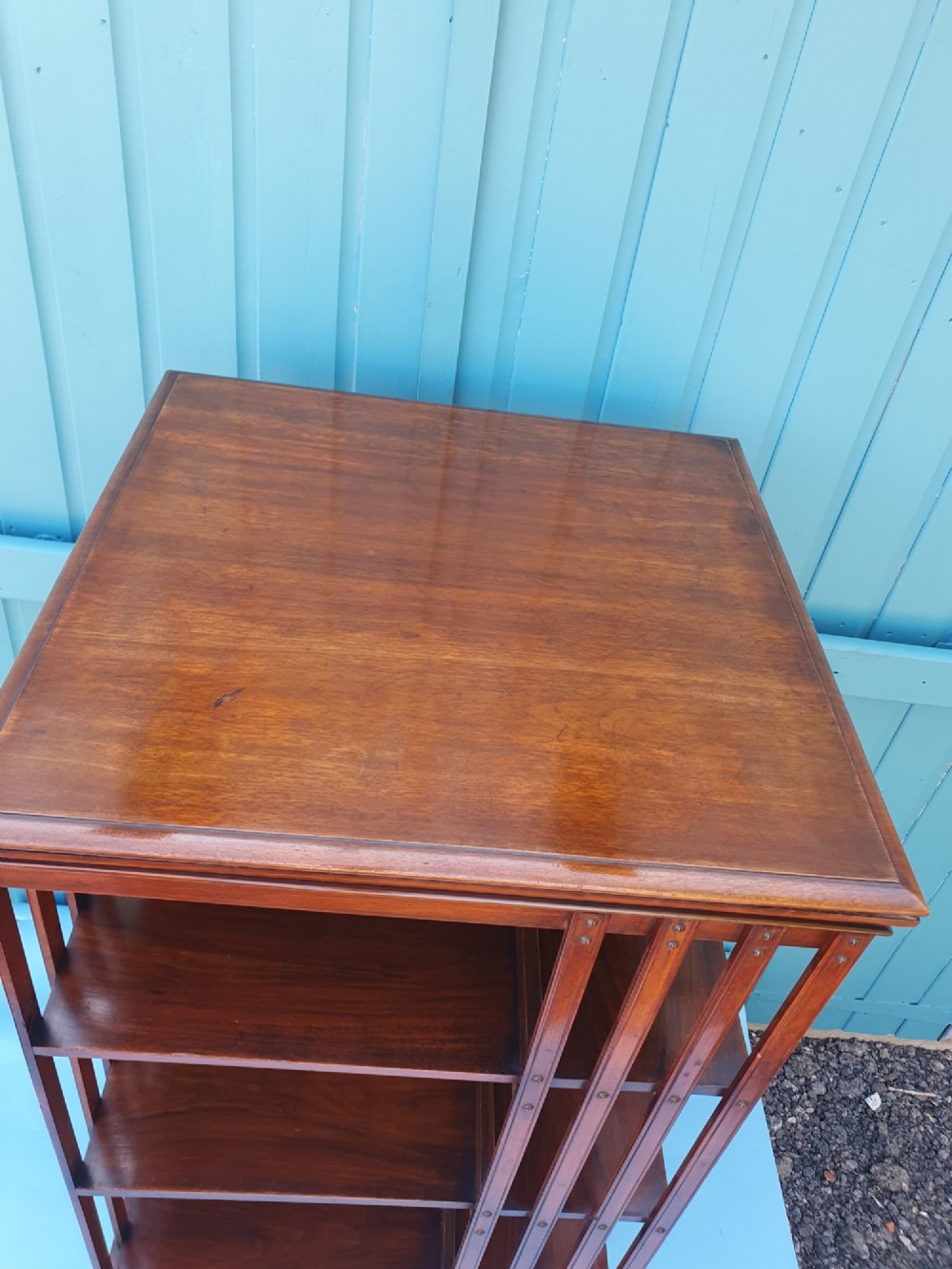 A four-tiered Victorian walnut revolving bookcase featuring vertical slatted sides, open shelf compartments, and a square moulded top on castors. View III