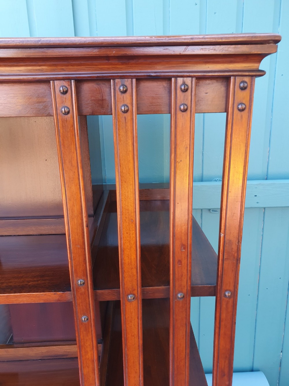 A four-tiered Victorian walnut revolving bookcase featuring vertical slatted sides, open shelf compartments, and a square moulded top on castors. View V