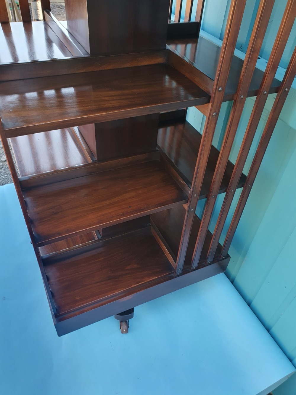 A four-tiered Victorian walnut revolving bookcase featuring vertical slatted sides, open shelf compartments, and a square moulded top on castors. View VI