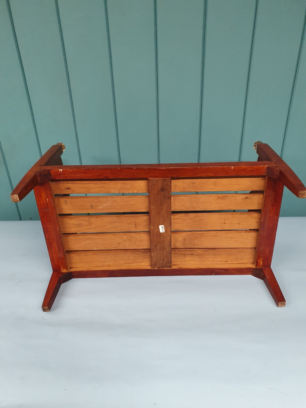 A small antique wooden doll bed with hand-painted floral motifs on the headboard and footboard, a slatted frame, and clear glass finials on four corner posts. View IV