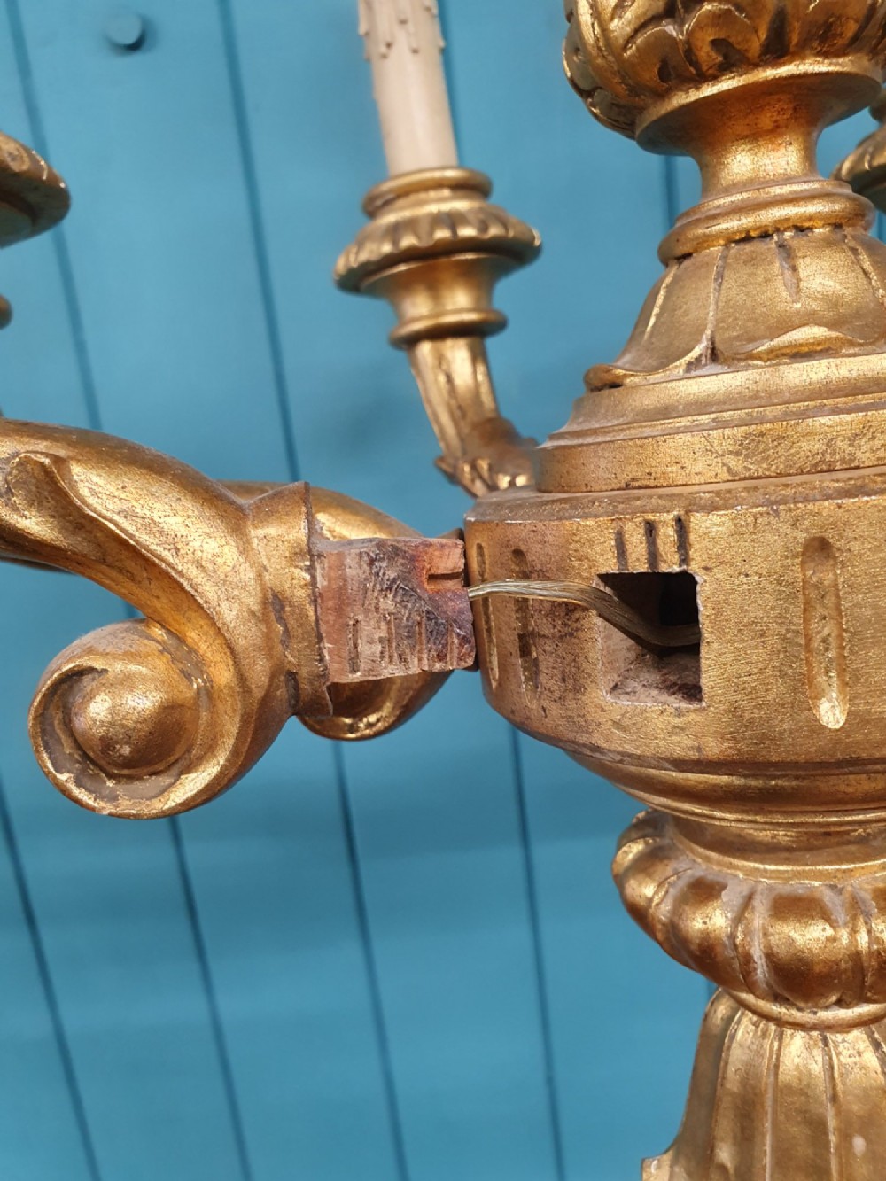 A Victorian circa 1890 six-arm giltwood chandelier featuring carved scroll arms, fluted details, and faux candle sleeves. View IV