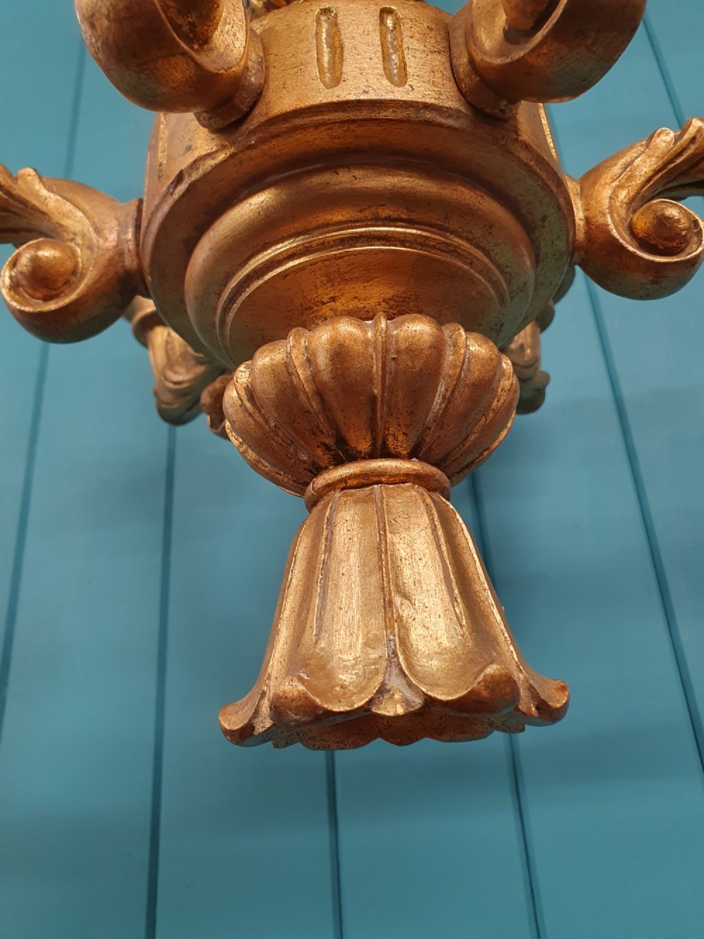 A Victorian circa 1890 six-arm giltwood chandelier featuring carved scroll arms, fluted details, and faux candle sleeves. View V