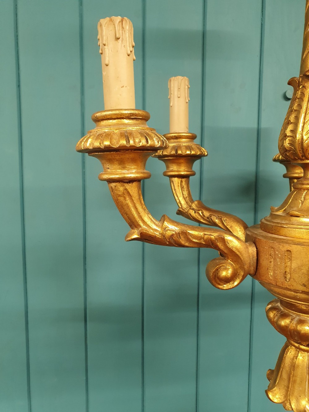 A Victorian circa 1890 six-arm giltwood chandelier featuring carved scroll arms, fluted details, and faux candle sleeves. View VI