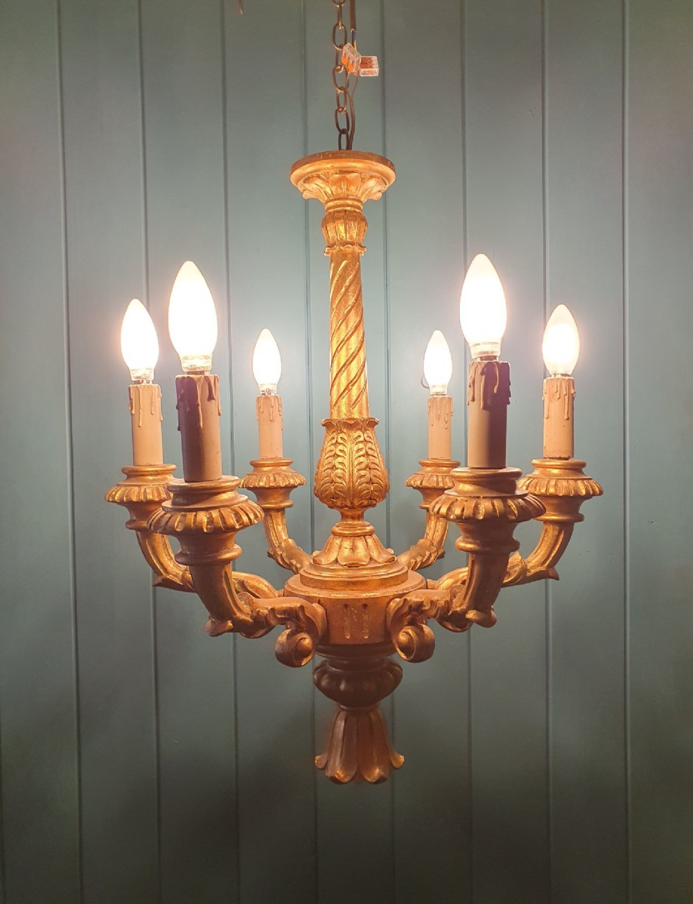 A Victorian circa 1890 six-arm giltwood chandelier featuring carved scroll arms, fluted details, and faux candle sleeves. View IX