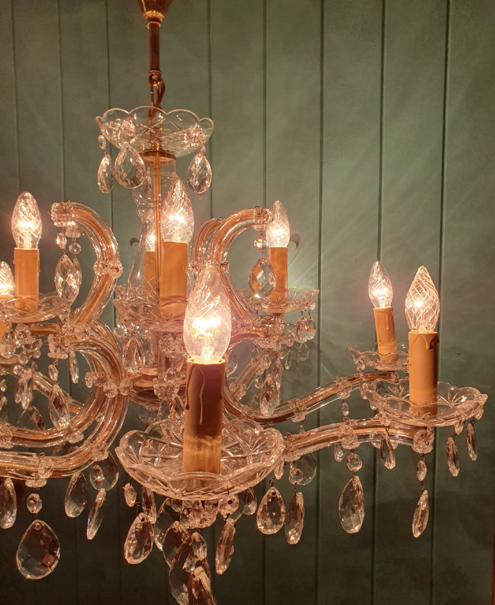 A matched pair of early 20th-century twelve-arm crystal chandeliers with faceted glass drops, curved arms, and brass mounts. View IV