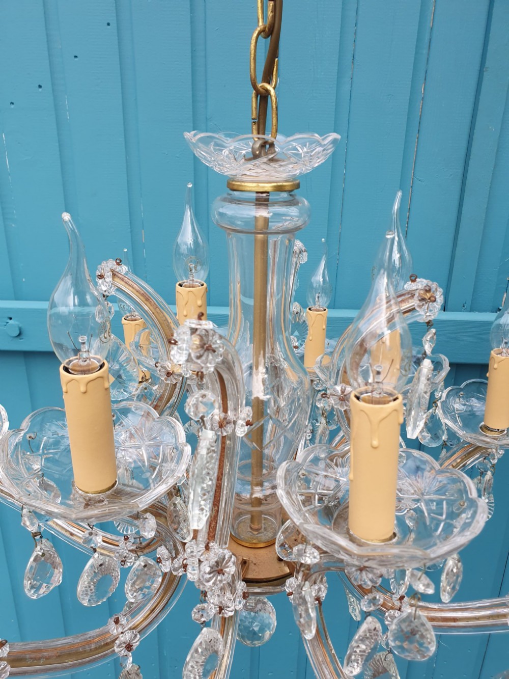 A matched pair of early 20th-century twelve-arm crystal chandeliers with faceted glass drops, curved arms, and brass mounts. View V