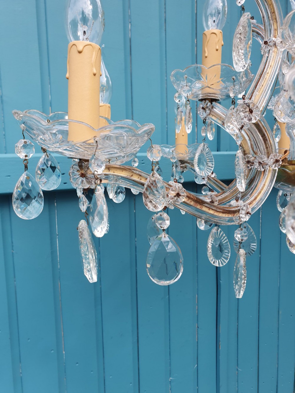 A matched pair of early 20th-century twelve-arm crystal chandeliers with faceted glass drops, curved arms, and brass mounts. View VI