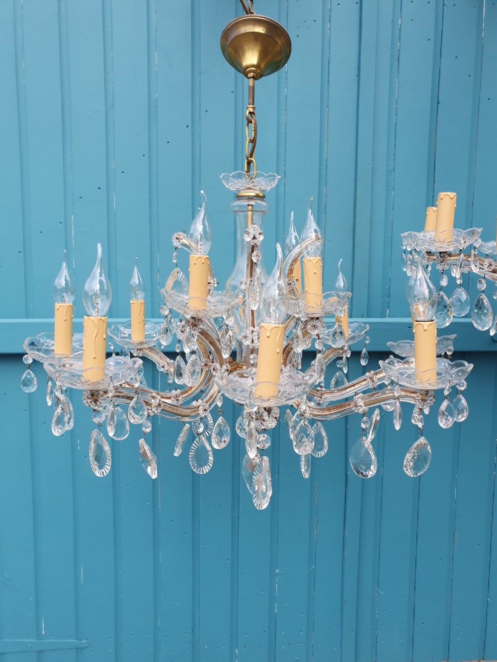 A matched pair of early 20th-century twelve-arm crystal chandeliers with faceted glass drops, curved arms, and brass mounts. View VII