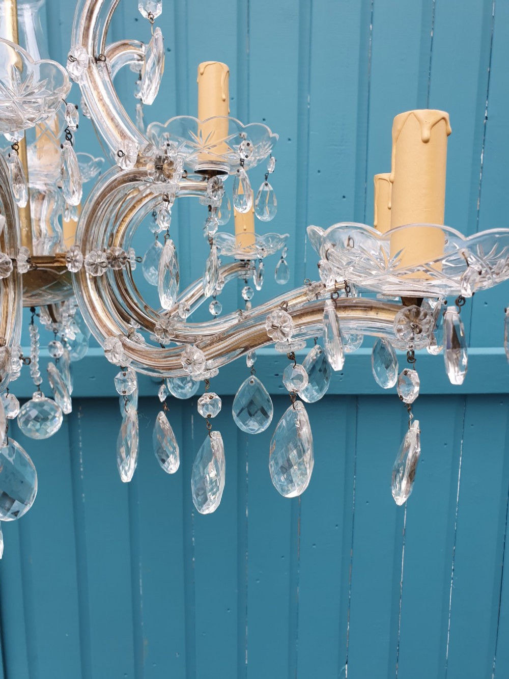 A matched pair of early 20th-century twelve-arm crystal chandeliers with faceted glass drops, curved arms, and brass mounts. View VIII