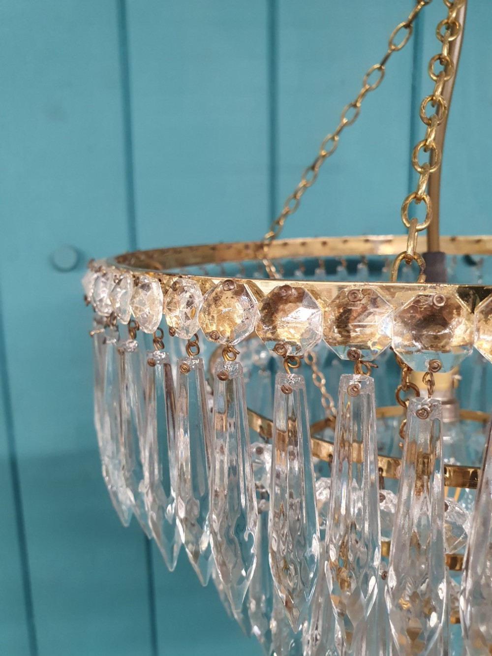 A tiered brass ceiling chandelier featuring multiple concentric rows of clear glass spike crystal prisms suspended by a chain. View VI
