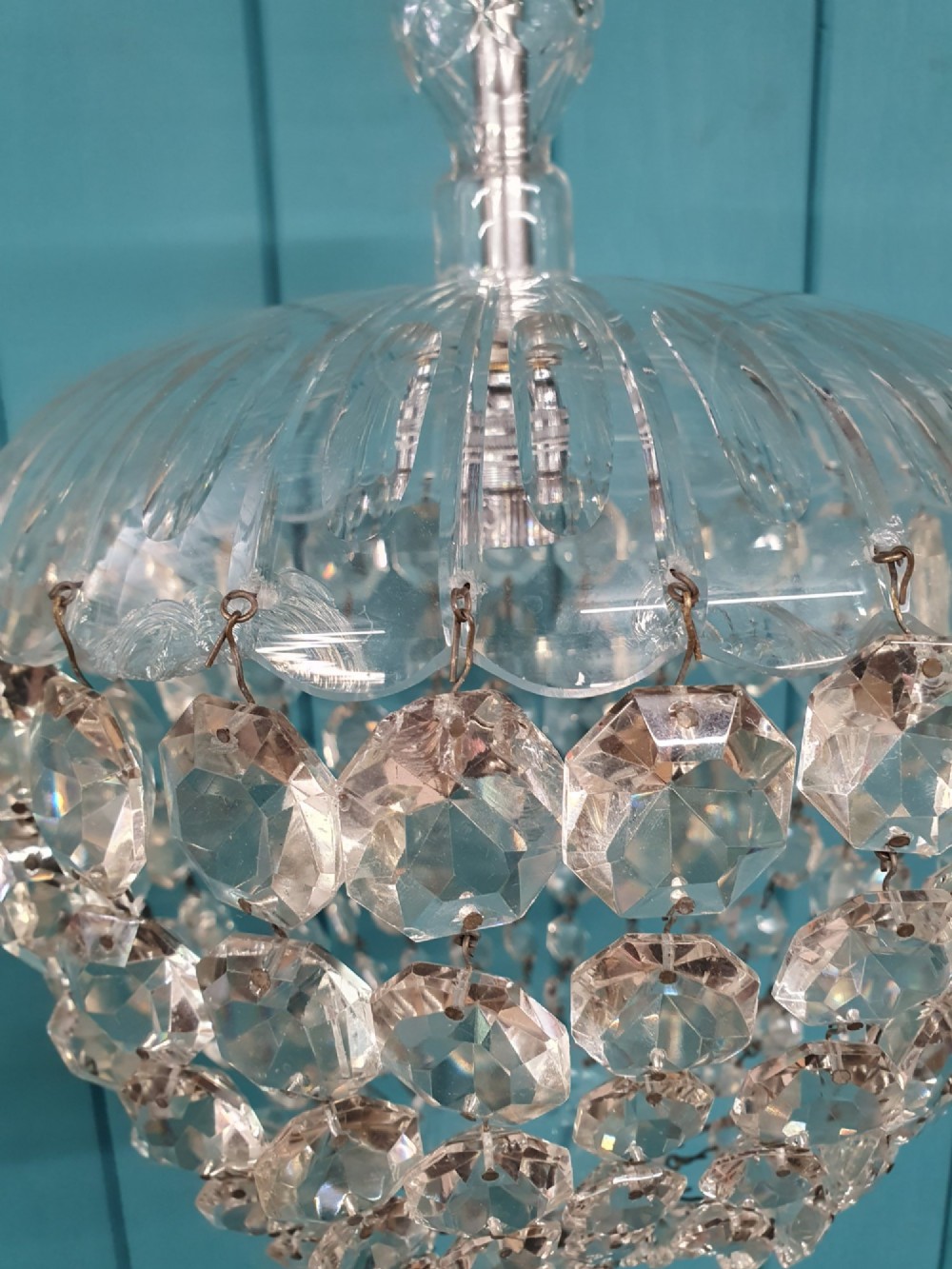 An early 20th-century dome-top chandelier with faceted crystal strands forming a rounded drop, suspended from a brass chain. View II