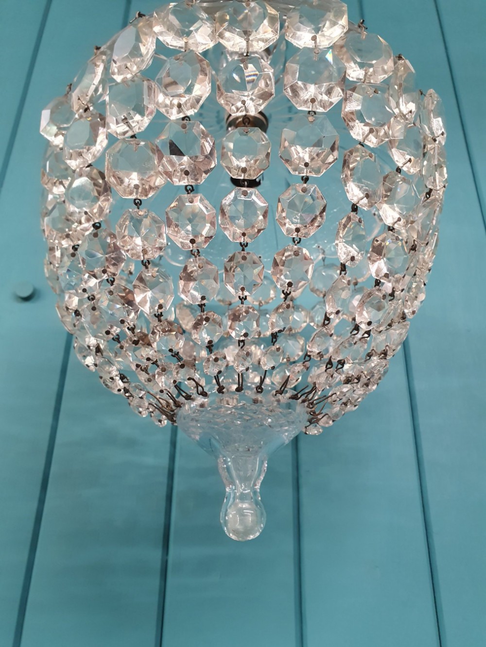 An early 20th-century dome-top chandelier with faceted crystal strands forming a rounded drop, suspended from a brass chain. View III