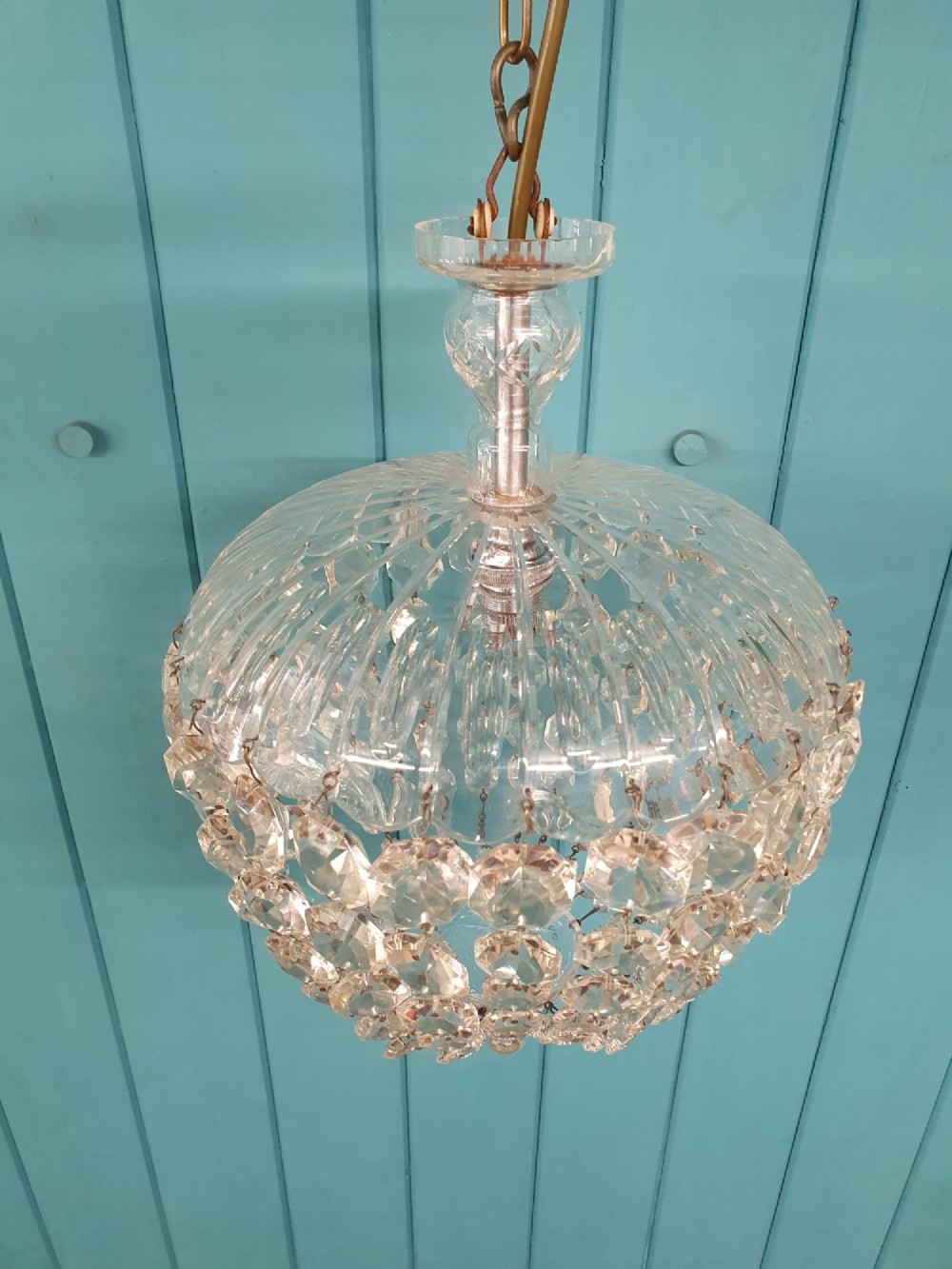 An early 20th-century dome-top chandelier with faceted crystal strands forming a rounded drop, suspended from a brass chain. View IV