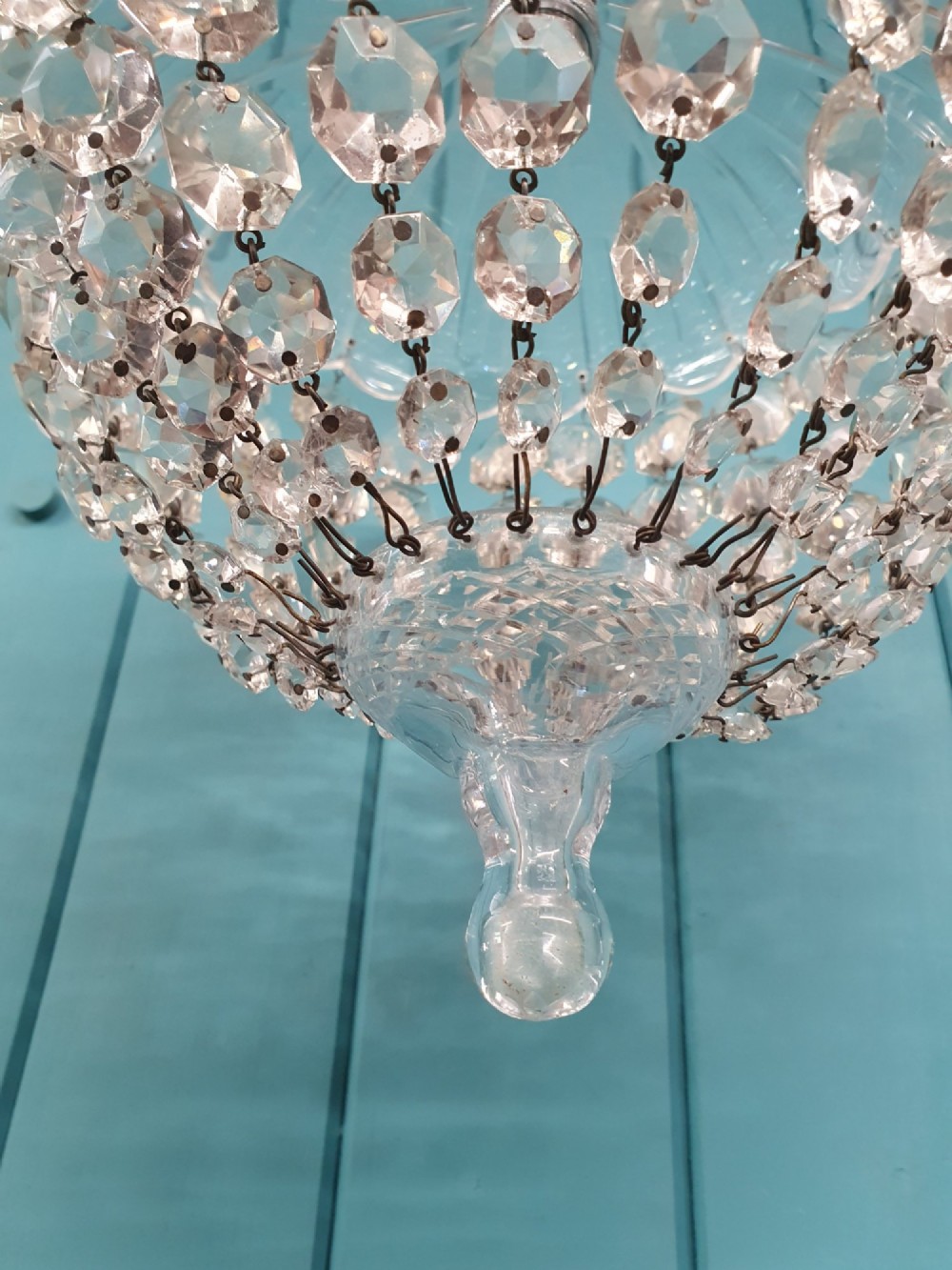 An early 20th-century dome-top chandelier with faceted crystal strands forming a rounded drop, suspended from a brass chain. View V