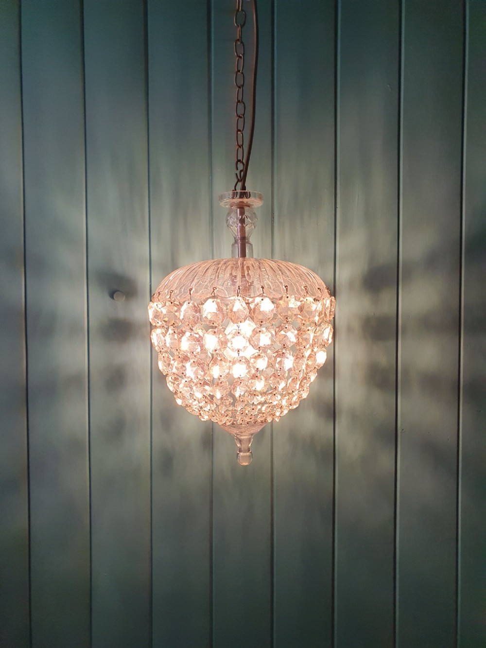 An early 20th-century dome-top chandelier with faceted crystal strands forming a rounded drop, suspended from a brass chain. View VI