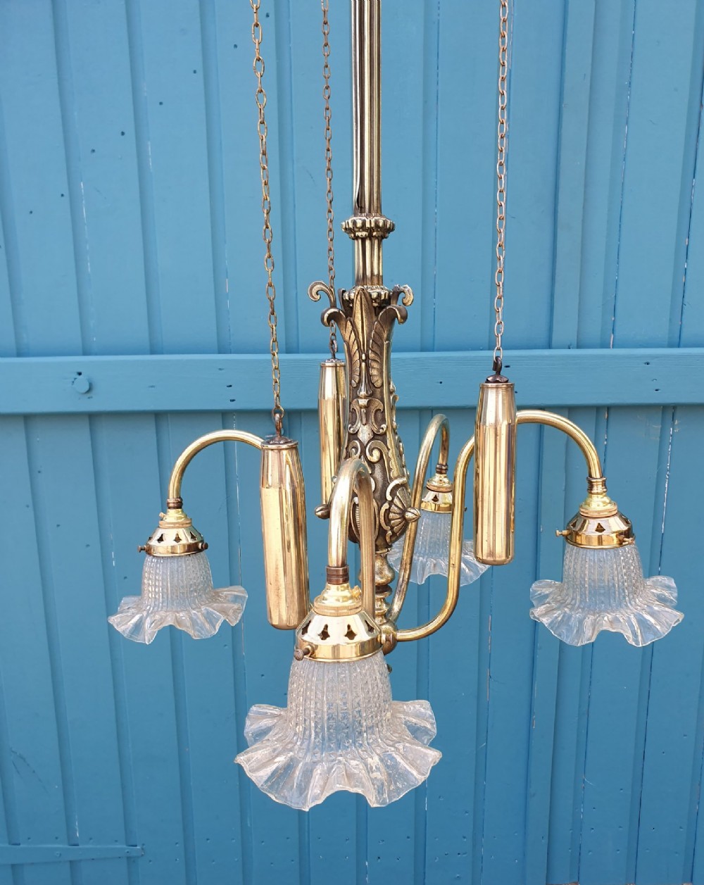 An antique brass four-arm rise and fall chandelier with curved arms, ruffled glass shades, and a counterweight pulley mechanism. View II