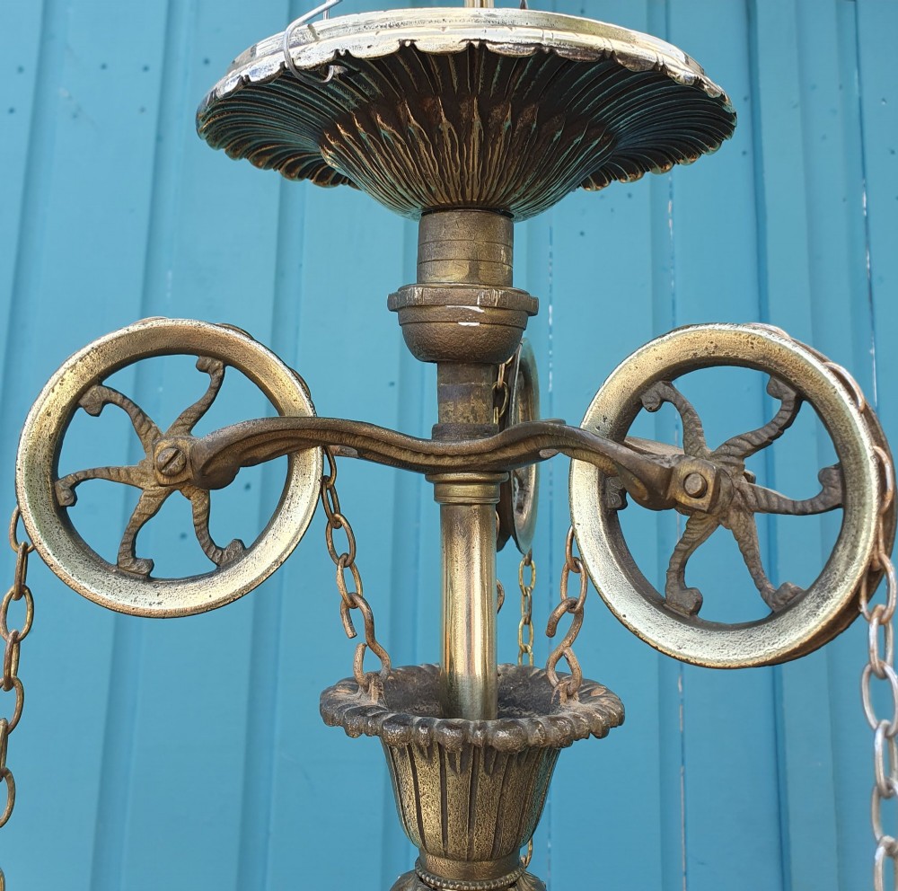An antique brass four-arm rise and fall chandelier with curved arms, ruffled glass shades, and a counterweight pulley mechanism. View V