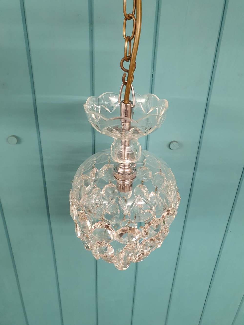 An early twentieth-century clear glass dome top chandelier featuring faceted crystal drops and a suspended hanging brass chain. View II