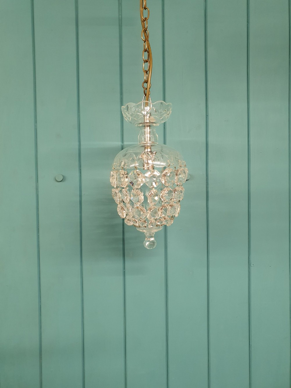 An early twentieth-century clear glass dome top chandelier featuring faceted crystal drops and a suspended hanging brass chain.