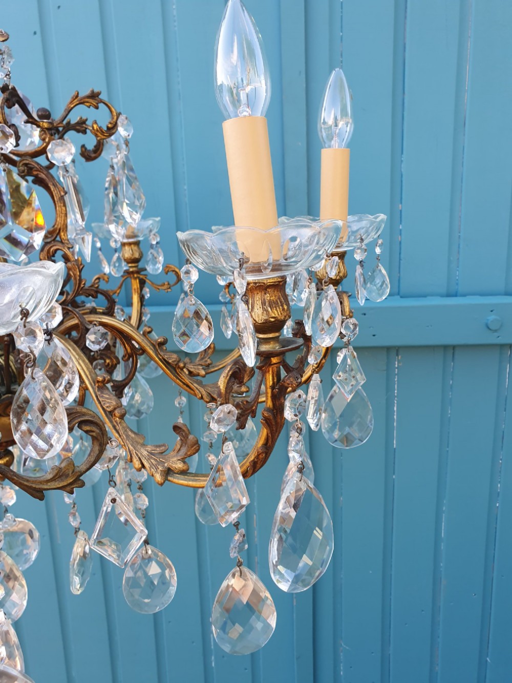 A ten-arm gilt brass chandelier with scrolling arms and suspended clear crystal drops. View III