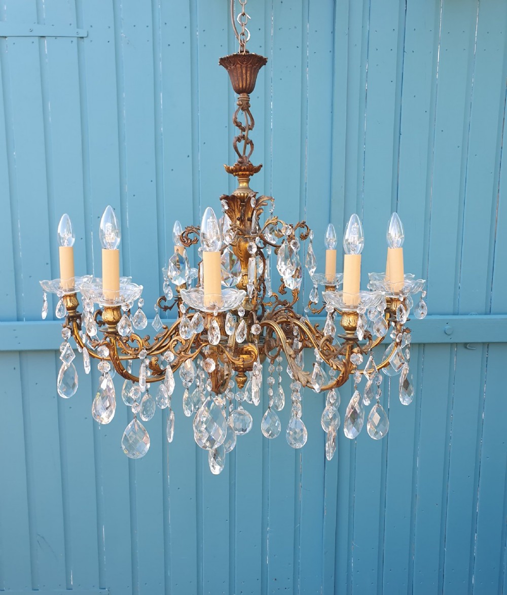A ten-arm gilt brass chandelier with scrolling arms and suspended clear crystal drops. View IV