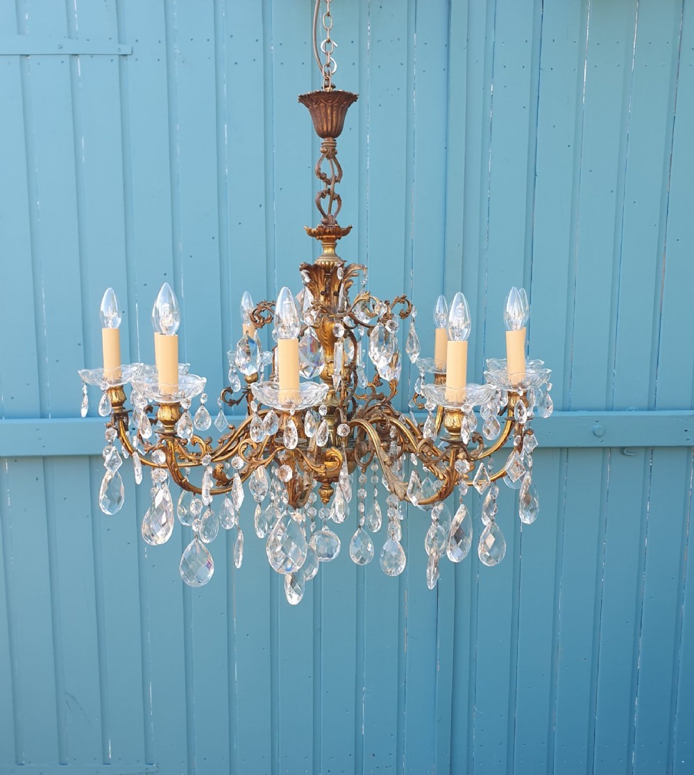 A ten-arm gilt brass chandelier with scrolling arms and suspended clear crystal drops.