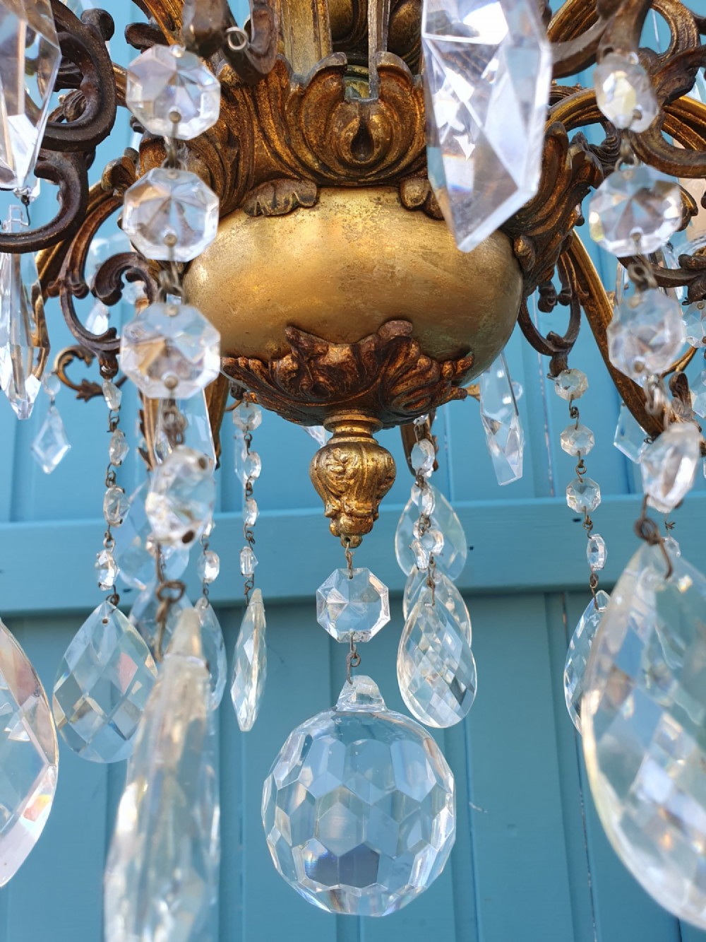 A ten-arm gilt brass chandelier with scrolling arms and suspended clear crystal drops. View V