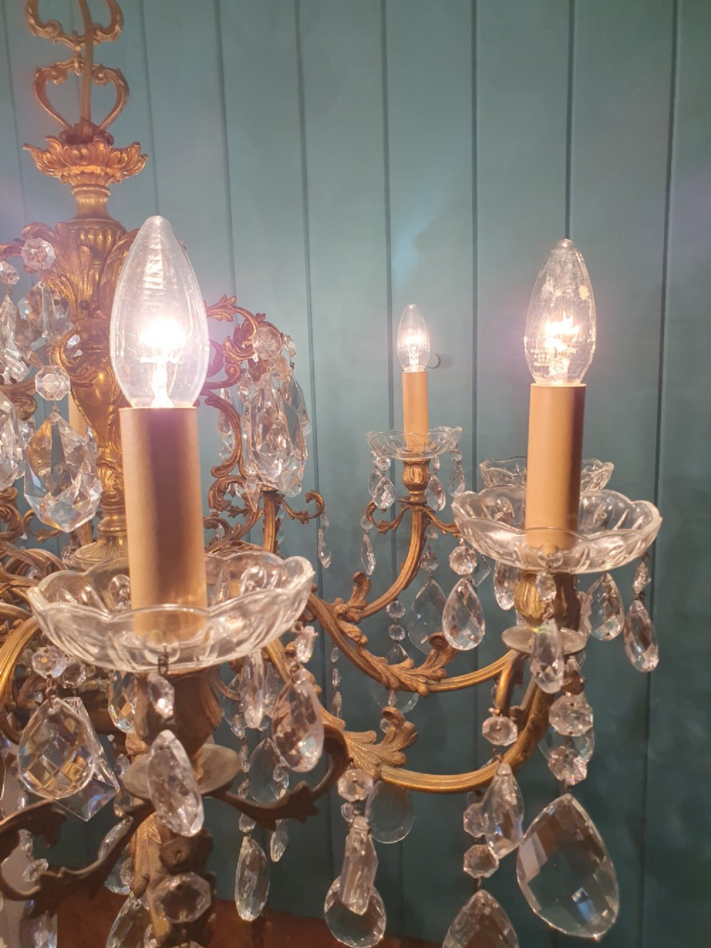 A ten-arm gilt brass chandelier with scrolling arms and suspended clear crystal drops. View VII