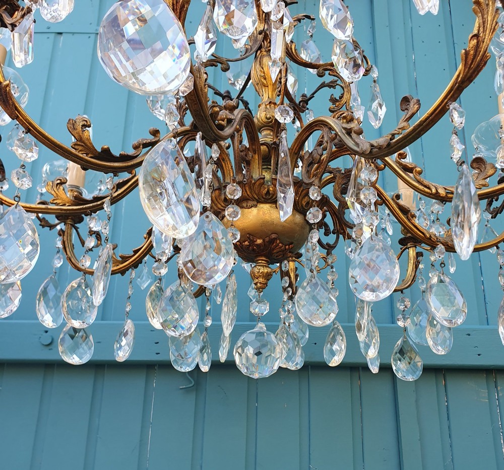 A ten-arm gilt brass chandelier with scrolling arms and suspended clear crystal drops. View VIII