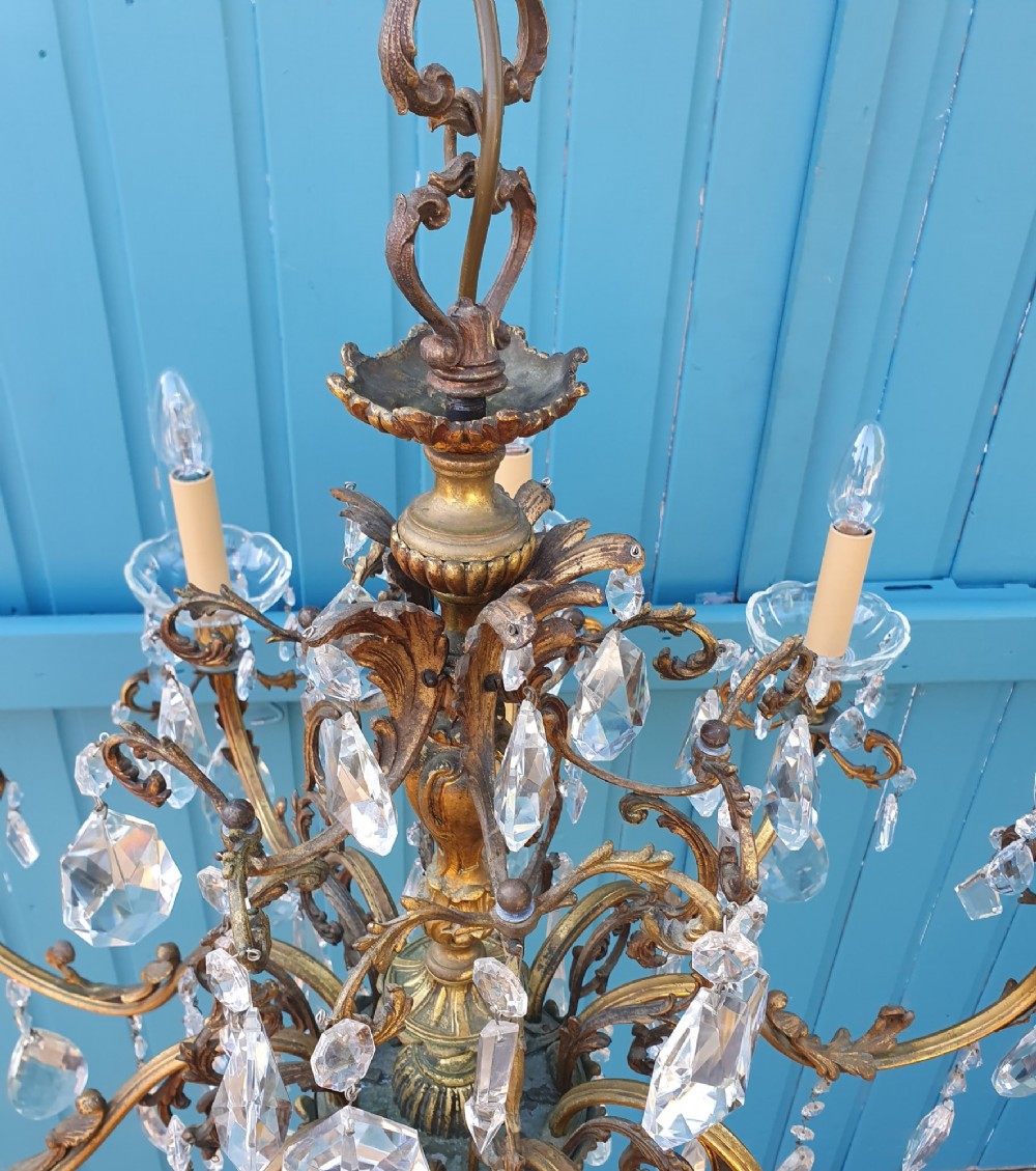 A ten-arm gilt brass chandelier with scrolling arms and suspended clear crystal drops. View X