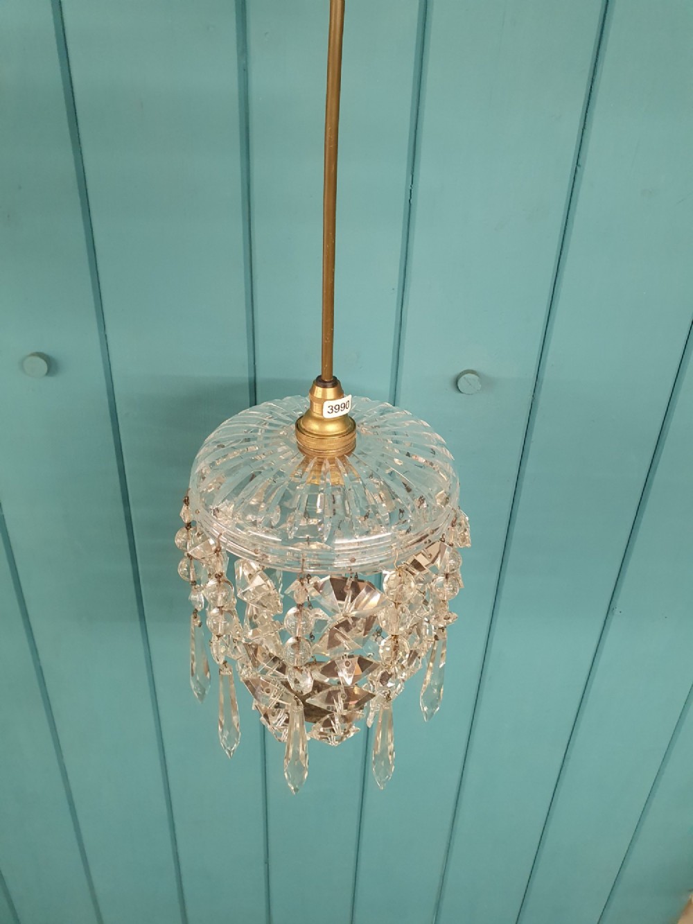 A small antique cut glass dome chandelier with suspended faceted crystal droplets mounted on a central brass stem. View II