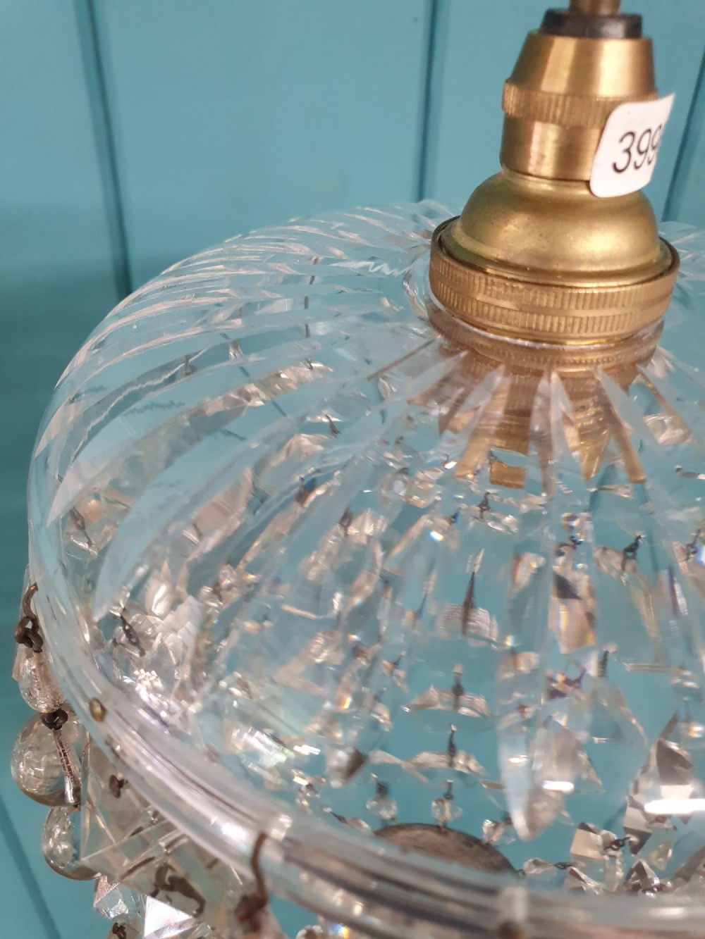 A small antique cut glass dome chandelier with suspended faceted crystal droplets mounted on a central brass stem. View III