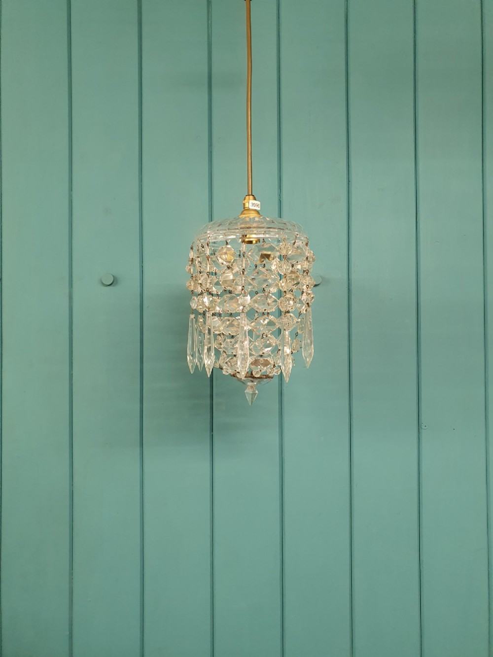 A small antique cut glass dome chandelier with suspended faceted crystal droplets mounted on a central brass stem.