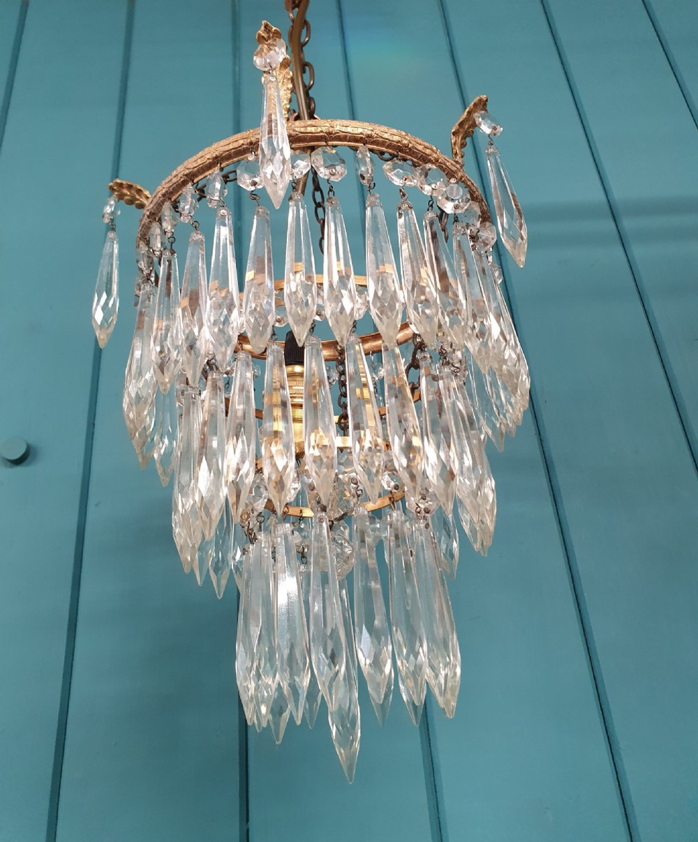 A small three-tier brass pendant chandelier with cascading clear glass icicle drops suspended from a brass chain. View III
