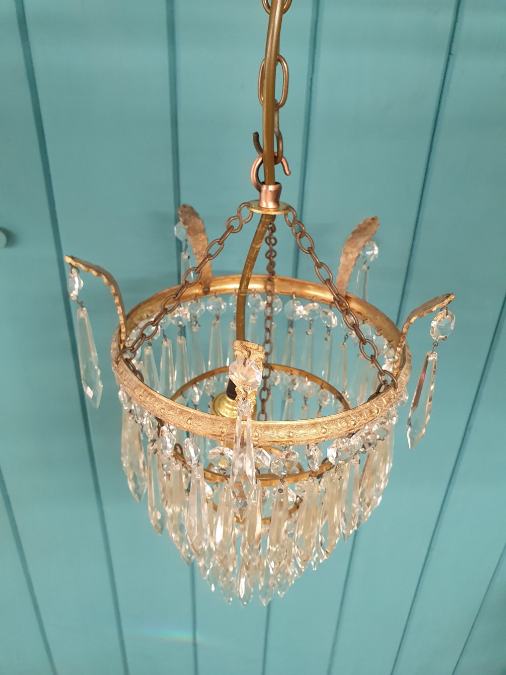 A small three-tier brass pendant chandelier with cascading clear glass icicle drops suspended from a brass chain. View IV
