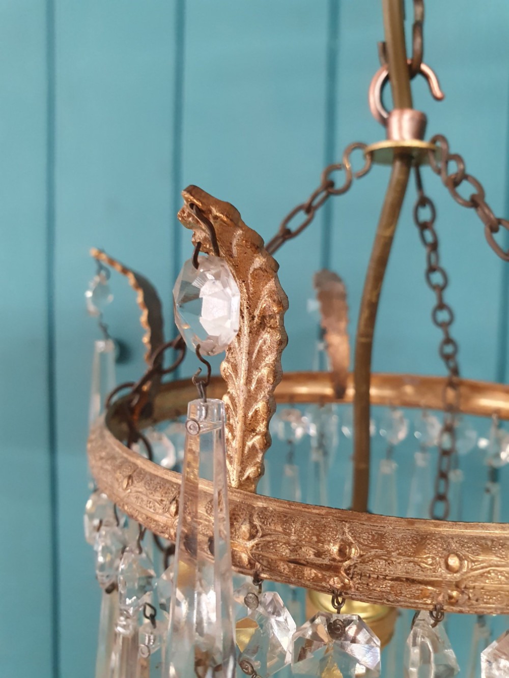 A small three-tier brass pendant chandelier with cascading clear glass icicle drops suspended from a brass chain. View V