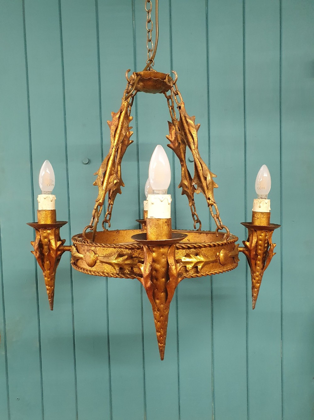 A late 19th-century French gilded metal coronet chandelier featuring a circular band adorned with leaf motifs and four candle-style light sockets suspended by chains.