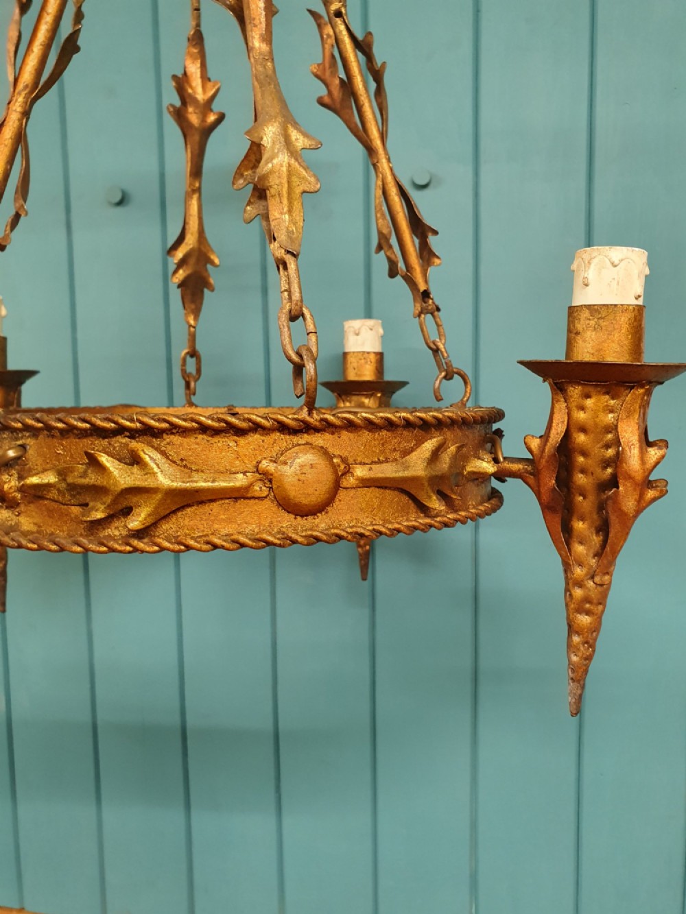 A late 19th-century French gilded metal coronet chandelier featuring a circular band adorned with leaf motifs and four candle-style light sockets suspended by chains. View V