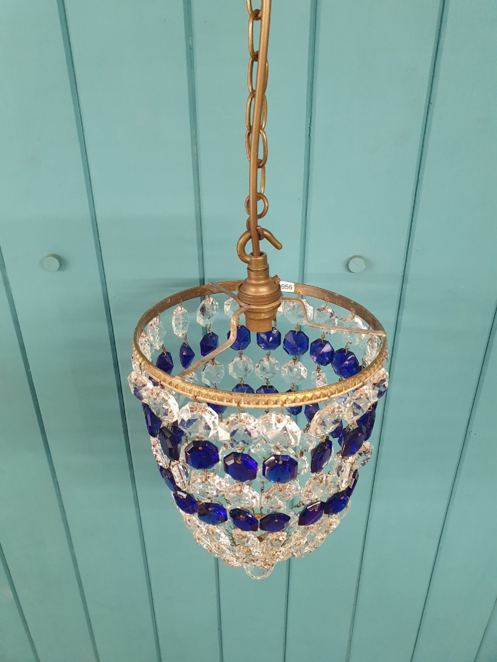 A small antique crystal bag chandelier featuring alternating concentric bands of clear and cobalt blue faceted glass beads suspended from a decorative brass rim and hanging chain. View II