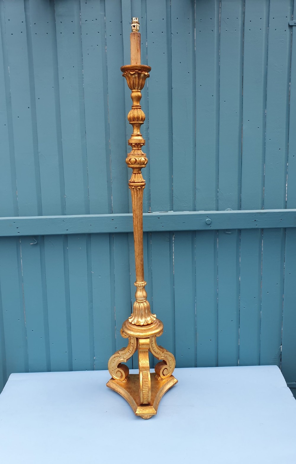 A late nineteenth-century carved giltwood standard lamp featuring a fluted column, ornamental knops, and a scroll-carved tripod base.