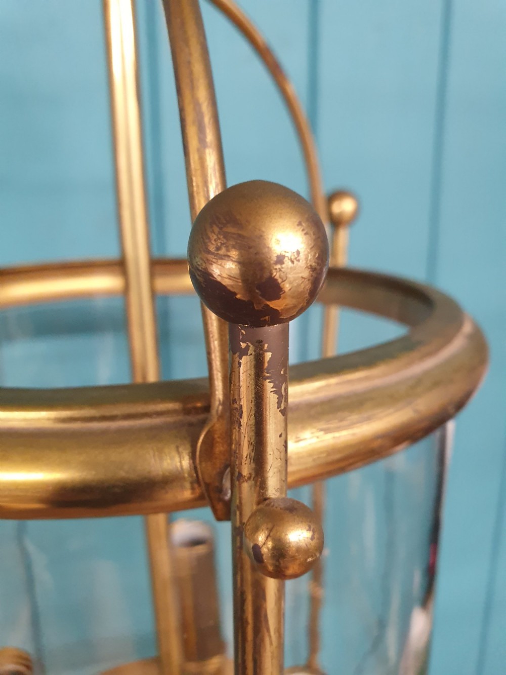An early 20th-century brass hall lantern with a cylindrical glass shade, internal light fitting, arched crown top, and suspension chain. View IV